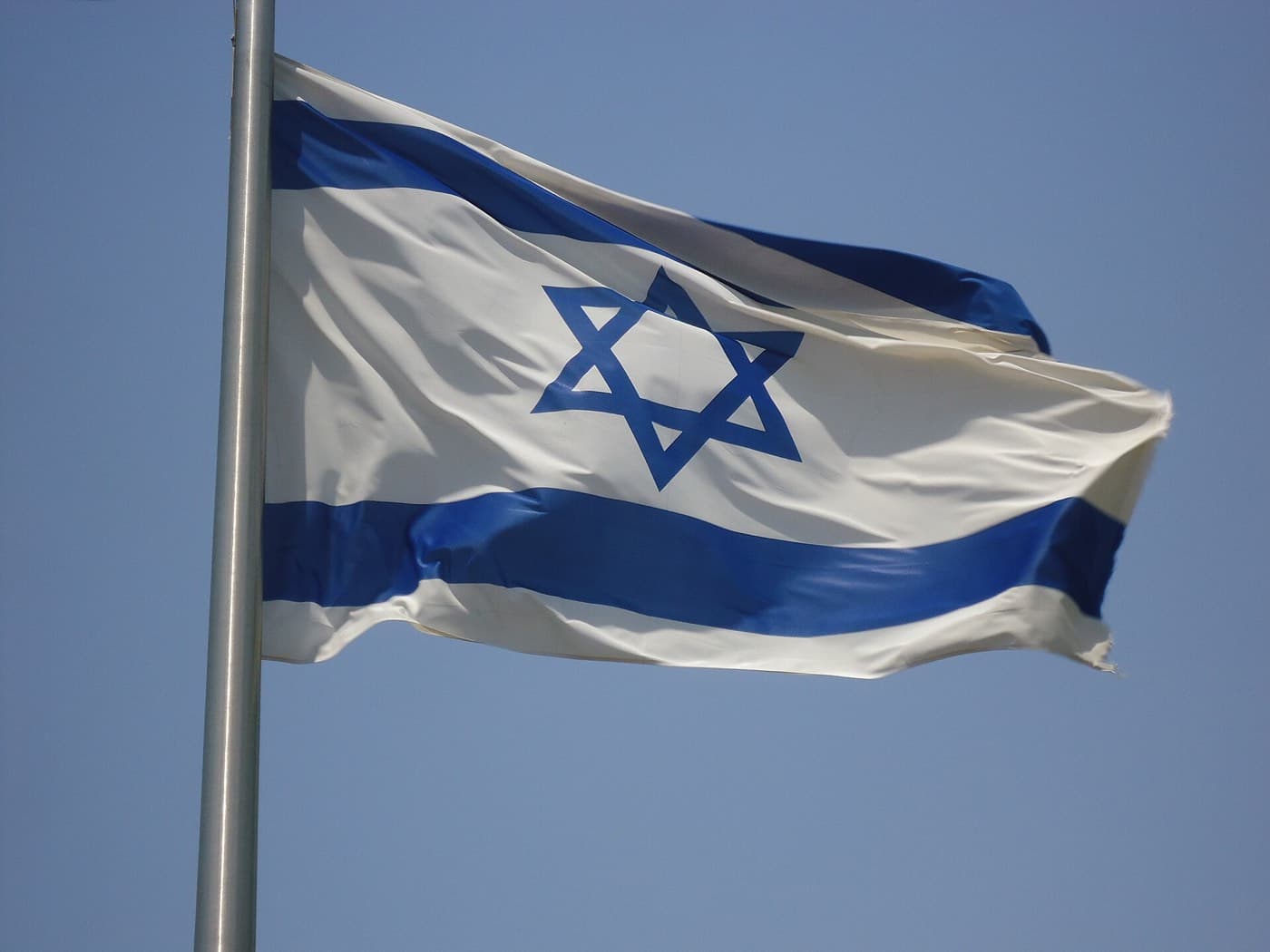 The national flag of Israel waving against a blue sky